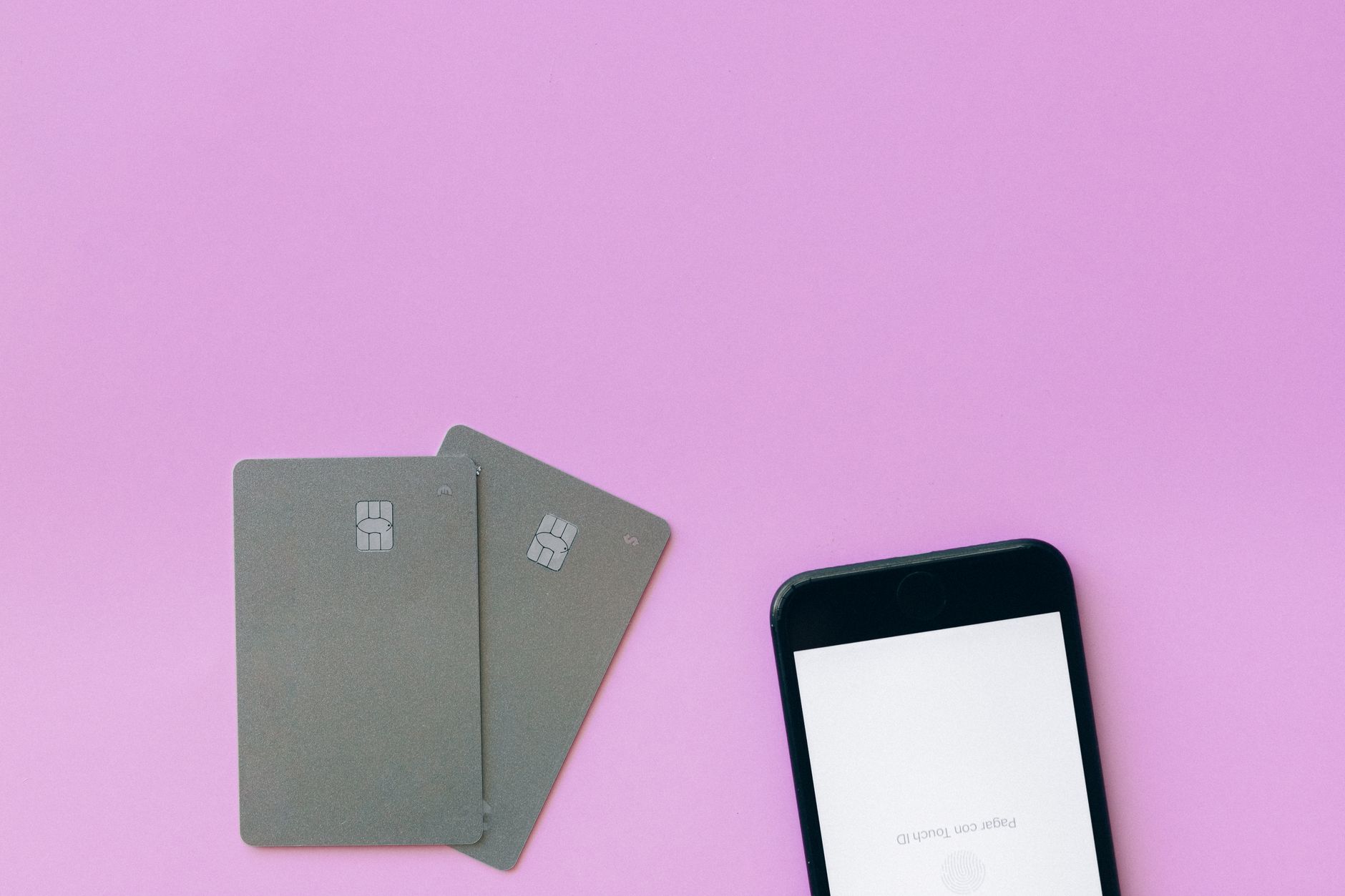 Mise en page à plat de cartes de crédit et de smartphone sur surface rose, symbolisant les solutions de paiement numérique.