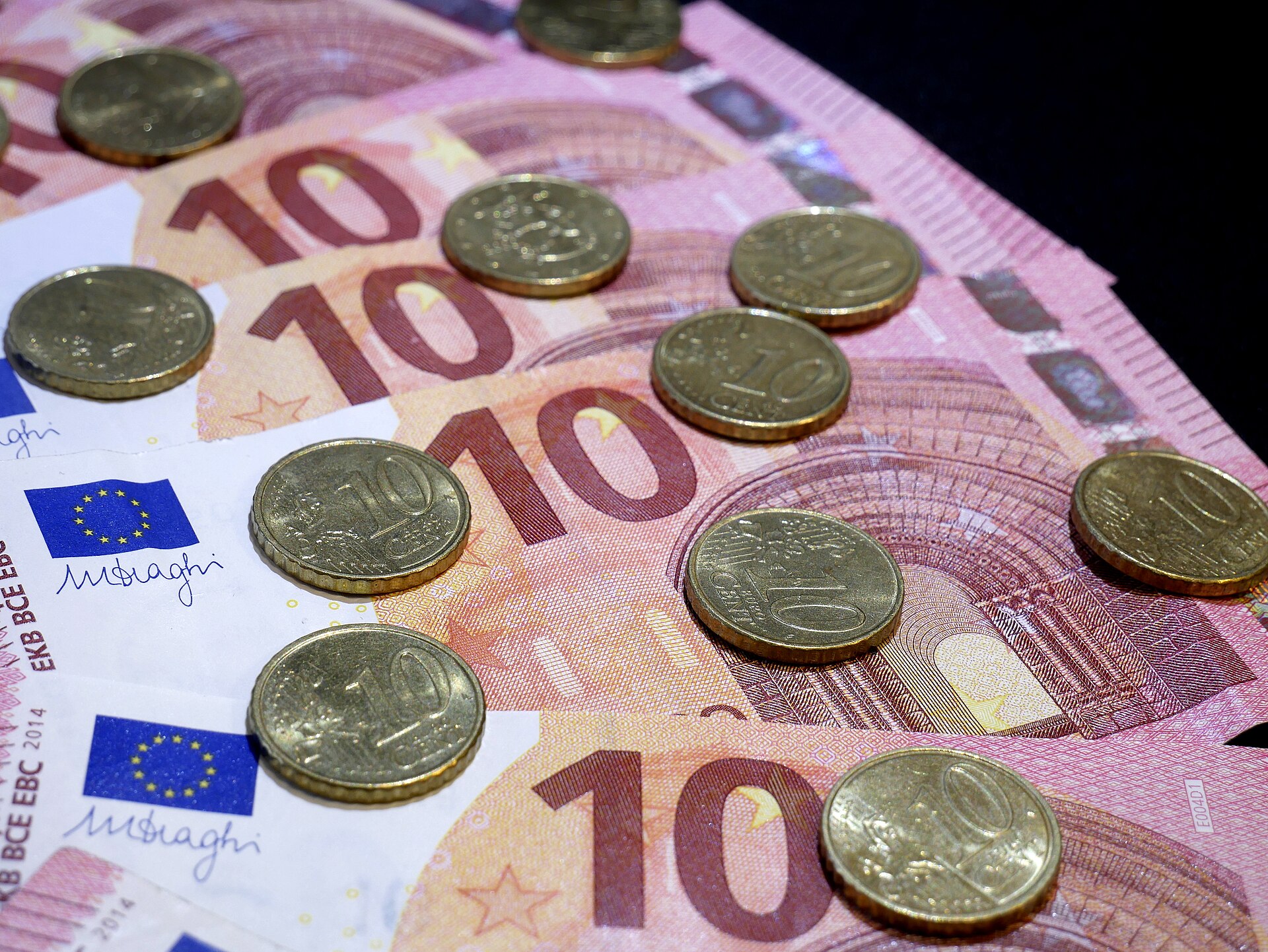 Billets de dix euros étalés en éventail et recouverts de pièces de dix centimes