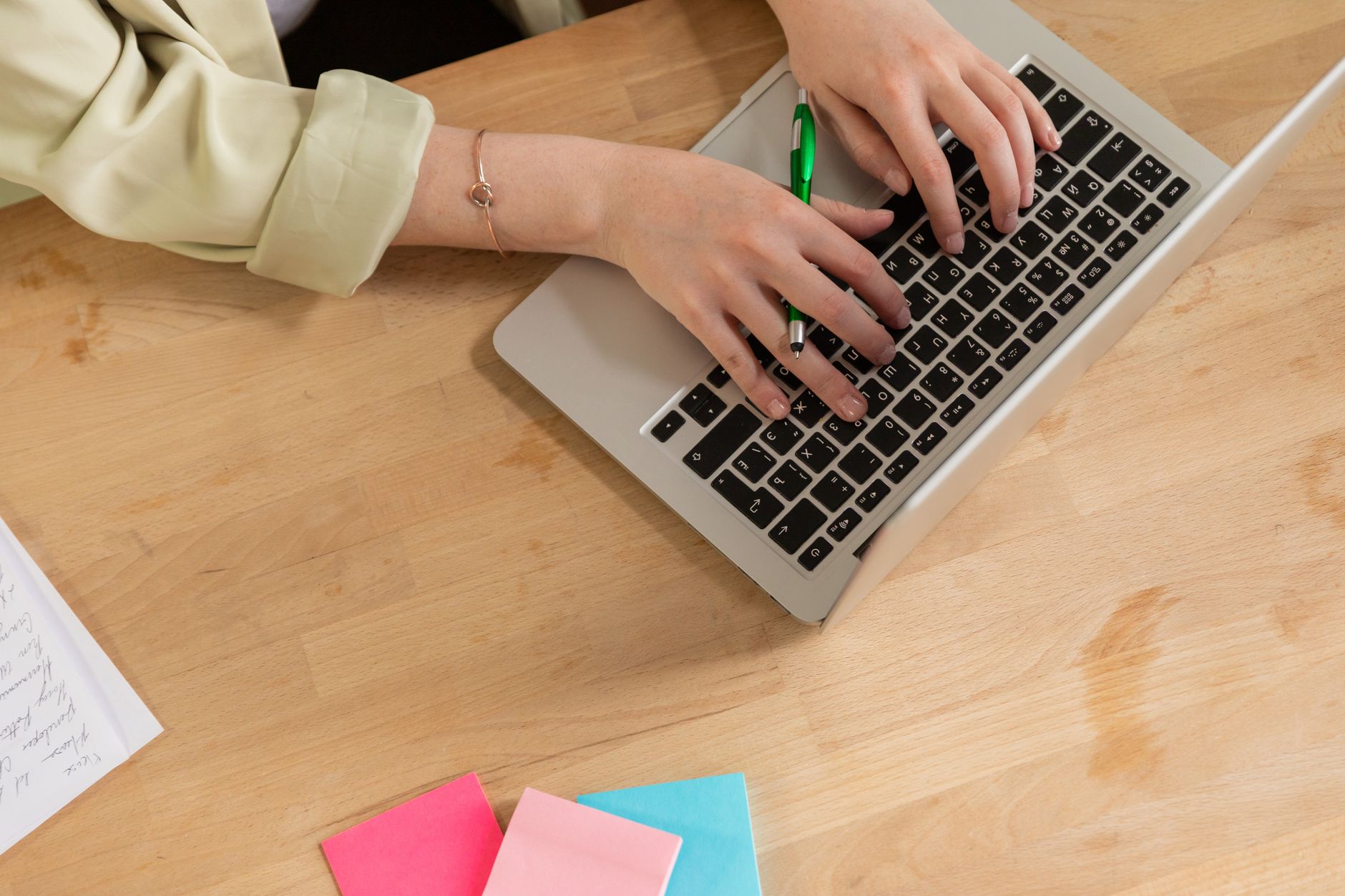 Mains d’une personne tapant sur le clavier d’un ordinateur portable sur un bureau en bois.