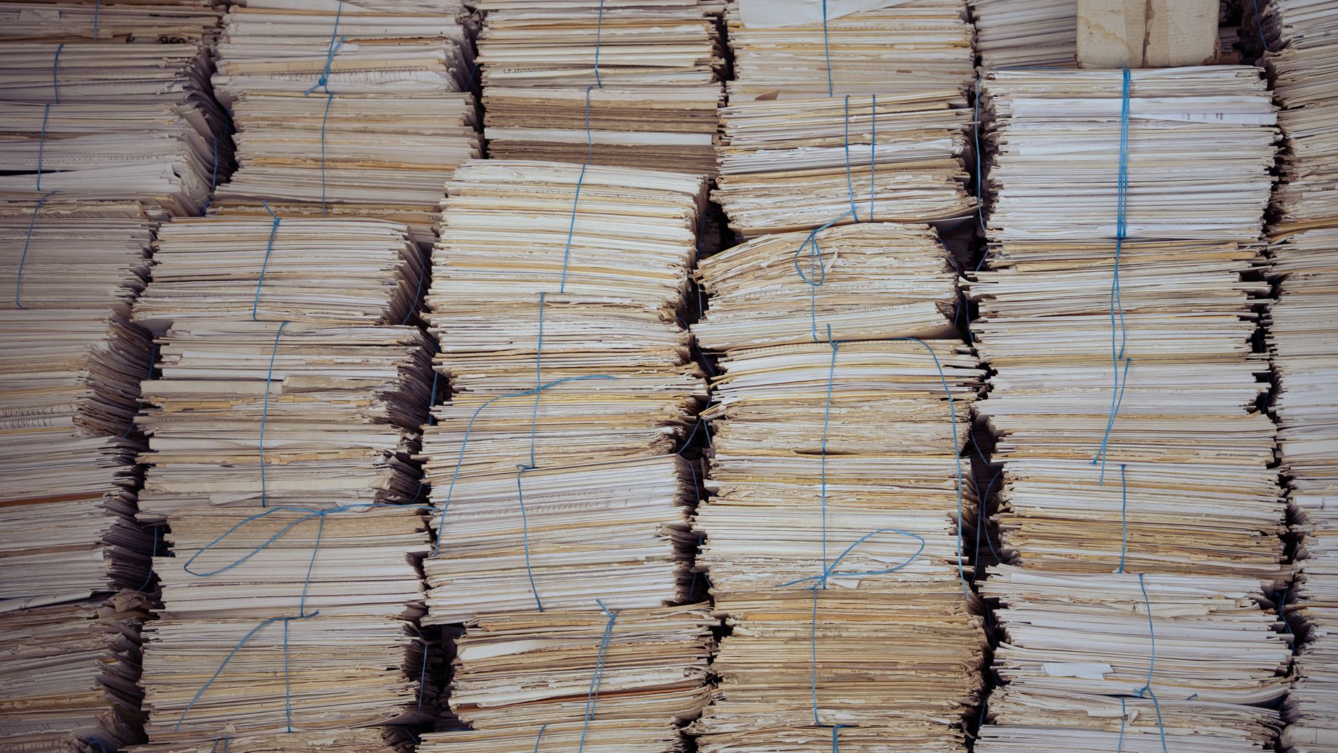 Piles de documents papier ficelés en liasses serrées